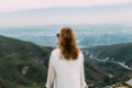 Femme assise sur une colline regardant l'horizon